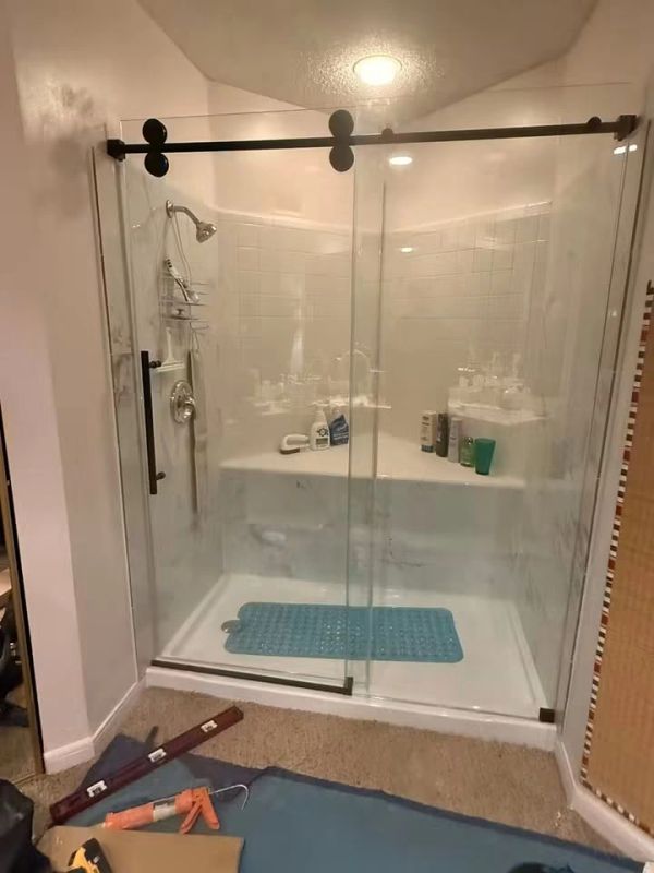 Modern glass shower with sliding doors and blue bath mat.