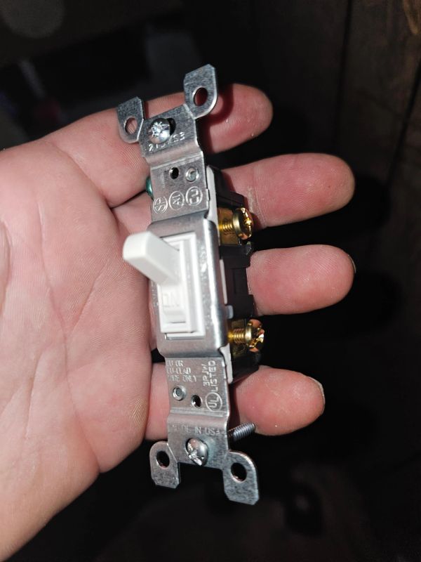 Hand holding a light switch.