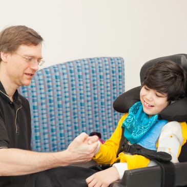 Man engaging with a boy in a wheelchair.