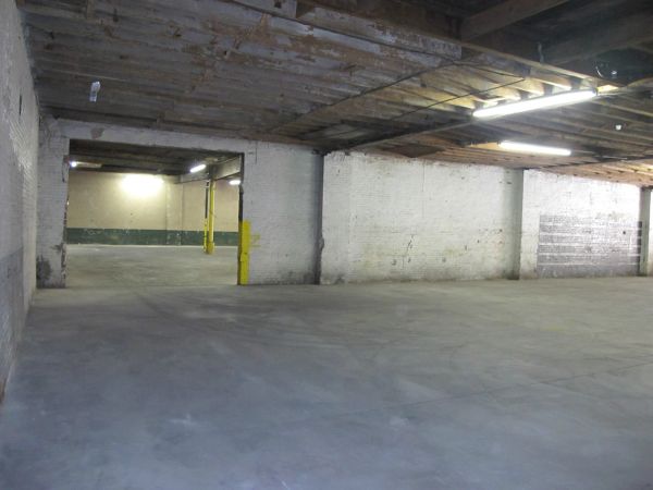 Empty industrial warehouse with concrete floor and fluorescent lighting.