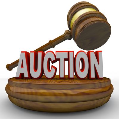 A wooden auction gavel resting on a base with the word 'AUCTION' in bold letters.