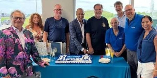Group of people celebrating around a cake at a table.