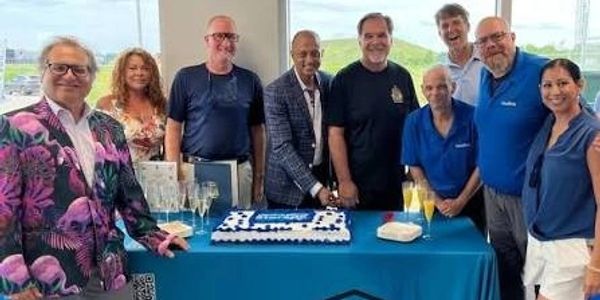 Group of people celebrating around a cake at a table.