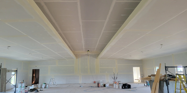 A large room under construction with drywall installation in progress.