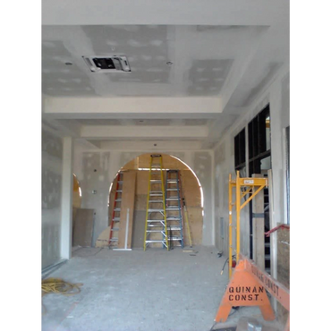 Interior under construction with ladders and drywall in progress.