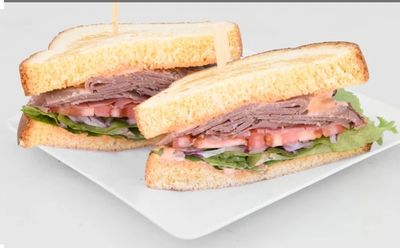 A fresh sandwich with roast beef, lettuce, and tomato on white bread.