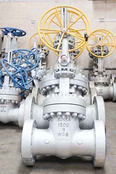 Industrial metal valves with yellow and blue handwheels in a factory.