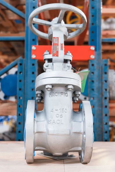 Industrial metal gate valve with handwheel in warehouse setting.