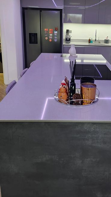 Modern kitchen with glossy cabinets and a sleek island featuring decorative items and LED lighting.