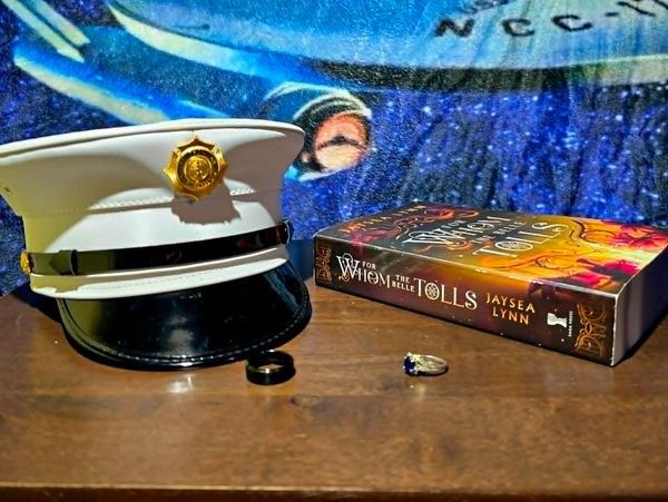 Marine hat, rings, and a book on a table with a starship mural.