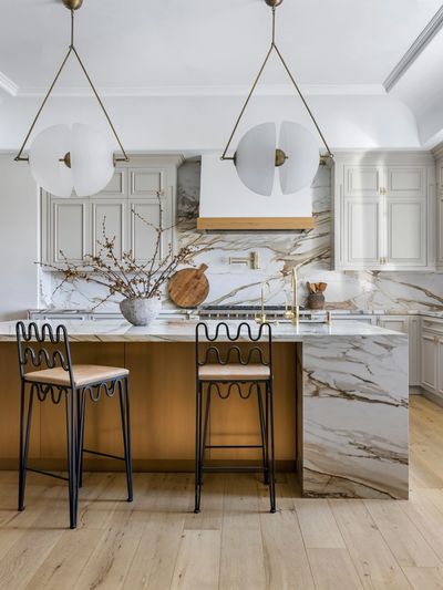 Gold Calacata kitchen with grass accents and brass hood with calacatta macchia vecchia porcelain