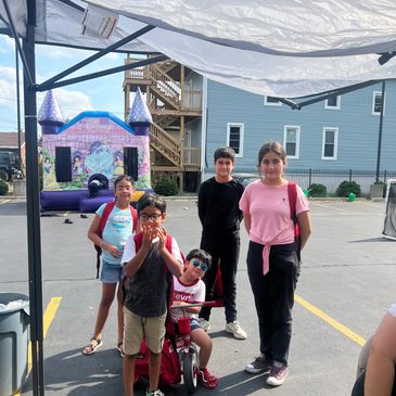 Group of kids posing in a parking lot with a bounce house.