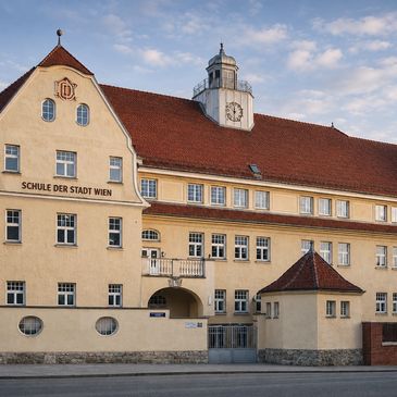 Historic school building in Vienna with classic architecture and clock tower.