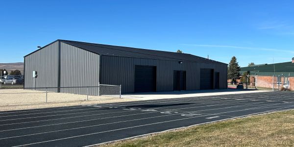 Large metal building next to a running track on a sunny day.
