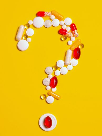 A variety of multi-colored shapes and sizes of pills forming a question mark