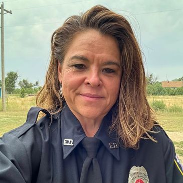 A woman in a dark police uniform outdoors.
