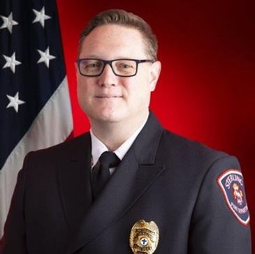 Portrait of a firefighter in uniform with an American flag background.