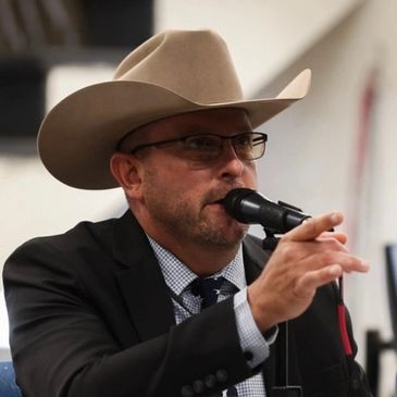Man in a cowboy hat speaking into a microphone.