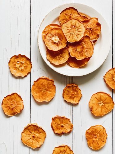 Dried persimmon slices on a white plate and table.