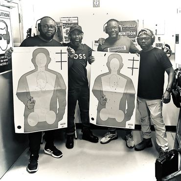 Four men at a shooting range holding target sheets with bullet holes.
