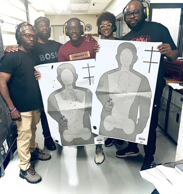 Group of five people holding paper shooting targets with bullet holes in a shooting range.