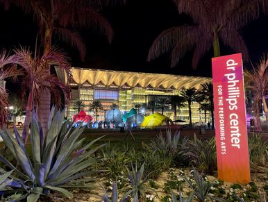 Night view of Dr. Phillips Center for the Performing Arts with palm trees.
