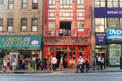 Busy street scene with shops and pedestrians in front of a red building named Social.