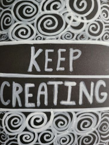 Blackboard with 'KEEP CREATING' surrounded by white swirls.
