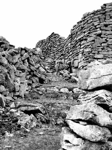 Ancient stone walls forming a rugged pathway in black and white.