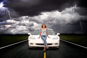 A woman sitting on a car hood