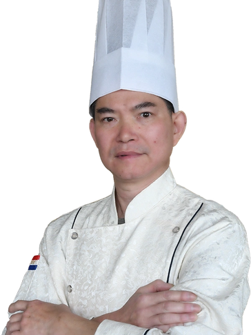 Portrait of Chef Wo Jun Lin wearing a white chef’s coat and hat, standing with arms crossed.