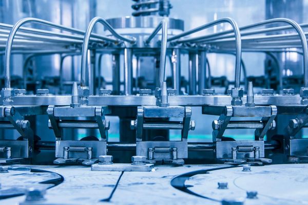 Close-up of metallic machinery with pipes and bolts in an industrial setting.