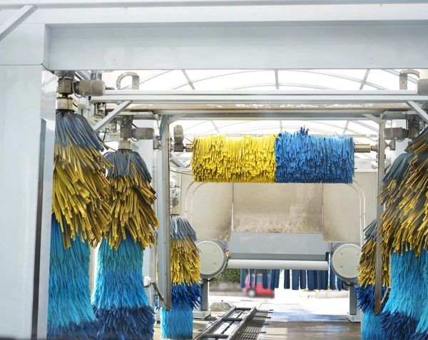 Car wash brushes in blue and yellow inside a car wash station.