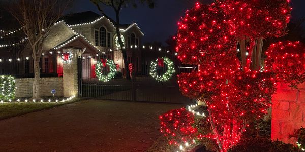 House decorated with Christmas lights and wreaths at night.