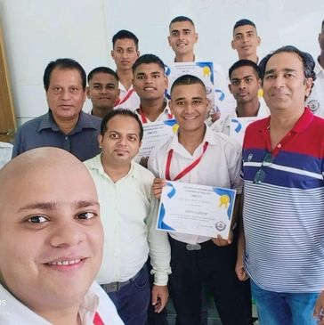 Group of men celebrating with certificates and smiling for a selfie.