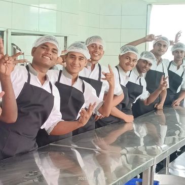 Group of kitchen staff posing and smiling in a clean kitchen.