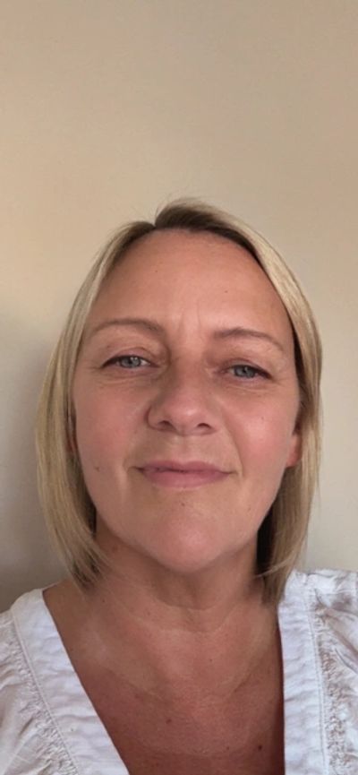 Smiling woman with short blonde hair in a white top.