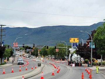 Road construction with traffic cones and workers on a city street.