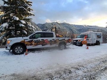 A snowy mountain scene with two vehicles parked on the roadside.