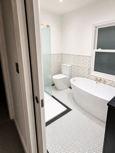 Modern bathroom with freestanding tub, toilet, and patterned tile floor.