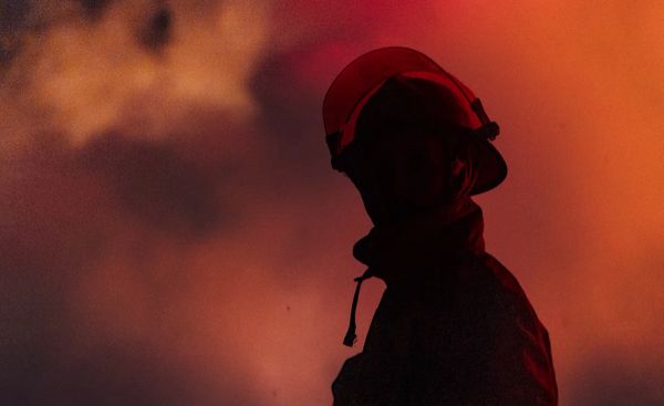 Silhouette of a firefighter against a fiery smoke background.