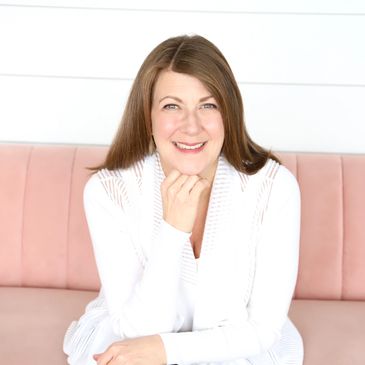 Photo of Sharyn Guhman on pink couch - she is a strategic leader who delivers successful outcomes 