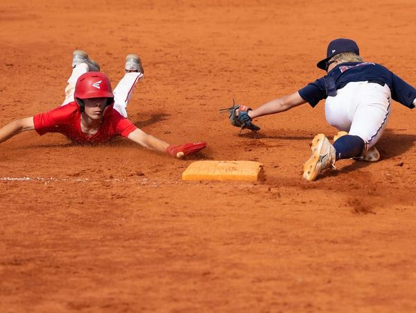 Two young baseball players dive near a base during a game.