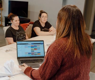 Three women having a meeting with a laptop schedule.
