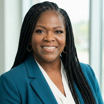 Confident woman with braided hair smiling in a professional setting.