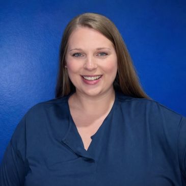 Smiling woman with long hair in a blue shirt against a blue background.