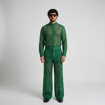 Man wearing a green patterned sheer outfit with sunglasses and black shoes.