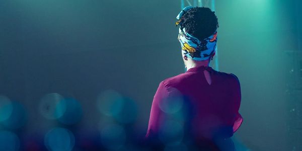 Image of woman with headscarf facing blurred audience.