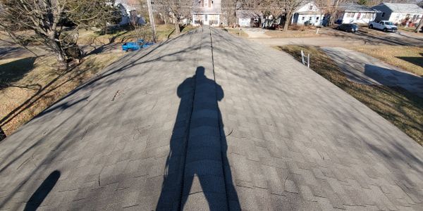 Inspector shadow visible while evaluating an asphalt shingle roof during a professional home inspect