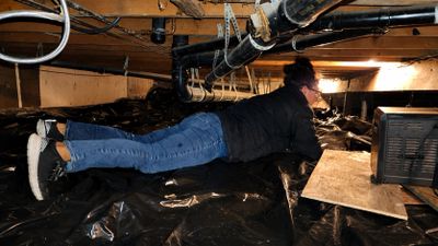 Gold Shield Inspections inspector evaluating structural framing within a crawlspace during a wood de